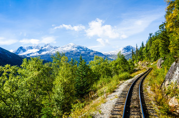 The stunning view of snow-capped mountains can be seen while travelling on the White Pass & Yukon Route Railroad built during the Klondike Gold Rush linking Skagway, Alaska with Whitehorse, Yukon. - 318062326