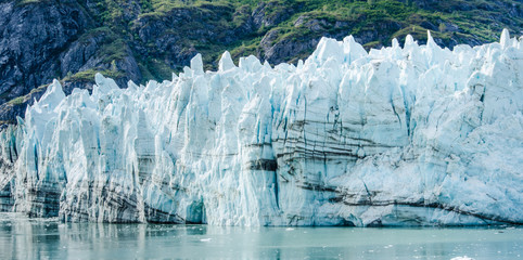 Close-up of Margerie Glacier where the dark lines are layers of rock formed from rock falls and streams that carry debris onto the ice. - 318062545
