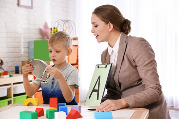 Speech therapist working with little boy in office