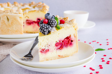 Delicious homemade puff pastry pie or cake with cream cheese filling and cherry on a white plate on a light stone background. Dessert for Valentine's Day. Horizontal orientation. Top view. Close up.