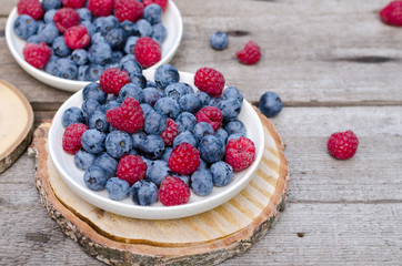 Still life with a blueberries and raspberries on an old wooden table, at the garden. Rural natural food style.