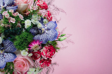 stylish trendy delicate bouquet with a variety of spring flowers, roses, orchids in a round box on a pink background. Copy space
