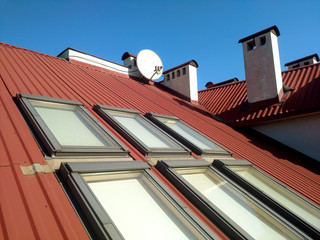 Red tiled house roof with attic windows. Roofing construction, window installation, modern...