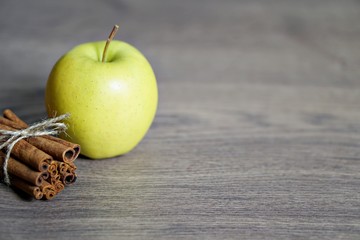Juicy colorful apples and cinnamon on wood table.