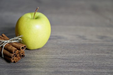 Juicy colorful apples and cinnamon on wood table.