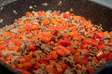 Raw minced meat with onions and peppers in a frying pan