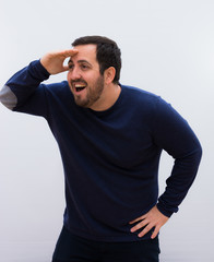 young handsome man looking amazed and happy, with hand over forehead looking far away, watching or searching against white wall.