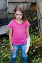 Frightened child with a bandage on his hand stands alone in the forest.