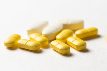 White and yellow drug pills on white background (selective focus)