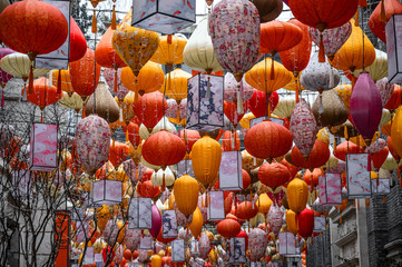 Lots of colorful different shapes oriental lanterns in famous touristic place hanging between the buildings. Preparation to celebrate the holiday and Lunar New year. Asian style traditional decoration © D. Kvasnetskyy