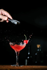Bartender in a bar mixing alcoholic cocktail. A professional bartender at work in a bar pours a red drink into a glass at a nightclub party.