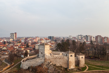 Fototapeta na wymiar Beautiful panorama of Pirot cityscape, with foreground ancient fortress Momcilov grad and city buildings and houses in the background during cloudy, cold winter day