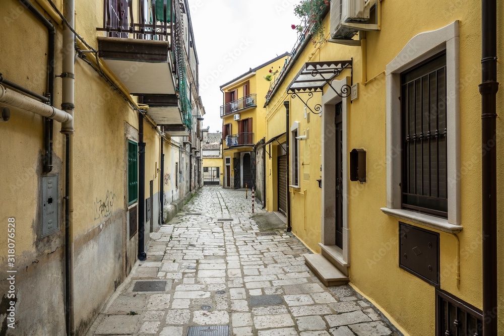 Sticker Road going between two yellow and brown buildings constructed closely next to each other