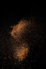 Fototapeta na wymiar Cocoa powder explosion in motion on black background. Chocolate dust.