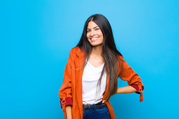 young pretty latin woman looking happy and friendly, smiling and winking an eye at you with a...