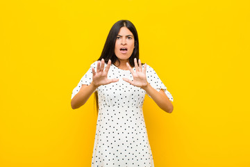 young pretty latin woman feeling terrified, backing off and screaming in horror and panic, reacting...