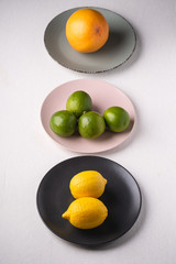 Lime, lemon, grapefruit in colorful plates on white background, angle view, vitamins and healthy food