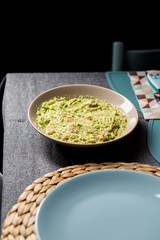 Green tasty guacamole sauce mexican food on a grey and blue fabrics