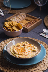 Tasty hummus chickpea food sauce on a plate on a blue and grey fabrics dinner table on a black background