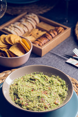 Green guacamole Mexican sauce food on a plate with bread toast slices close up still no a dark dinning table