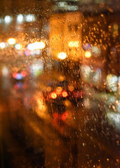 Rain drops on window with traffic on illuminated street