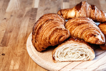 Many fresh croissants on wooden board.