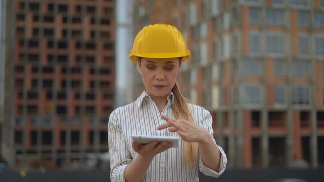 Closeup portrait of a female engineer. girl holds a tablet in her hands and works with a galagram. 4K