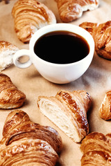 Cup of black freshly brewed coffee. Crispy croissant, breakfast in cafe.