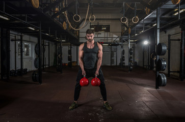 Obraz na płótnie Canvas Young veteran with scars strong fit sweaty muscular man big muscles holding two big old kettlebells with his hands preparing for hard core cross workout training in the gym for rehabilitation 