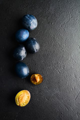 Fresh organic natural blue plums over black background with copy space