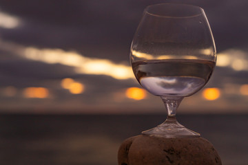 Snifter on the rocks on the beach at sunset. Golden hour. Sunset in a wine glass