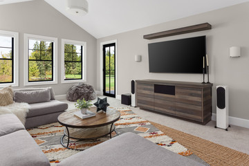Beautiful living room in new luxury home. Features L shaped sectional sofa, area rug, big screen tv, and elegant decor	