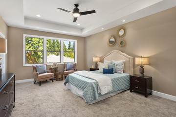 Bedroom in new luxury home with ceiling fan, chairs, pillows, and large windows