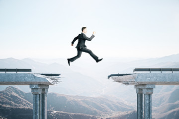 Businessman jumping over the gap in the bridge
