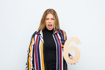 young pretty blonde woman angry, anger, disagreement, holding a number 6.