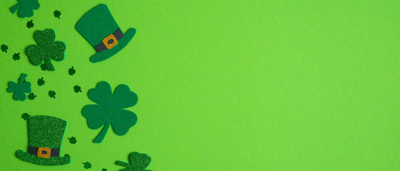 Happy St. Patrick's Day banner design. Top view shamrock leaf clovers and Irish elf hats on green...