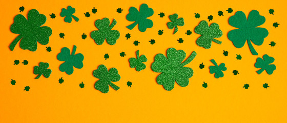 Shamrock four and three leaf clovers frame border on orange background. Happy St. Patrick's day...