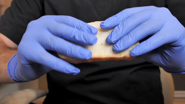 Cook in black suit touching and compresses a piece of the white bread testing whether it is fresh or not.