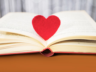 Red heart with old book concept. Greeting card for Valentine's day. Textile red heart for Valentines holiday. Romantic background and wallpaper