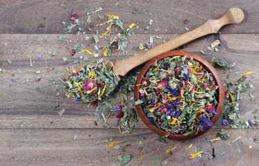 medicinal herbs in a wooden bowl. dry mint, hibiscus flowers, calendula petals, forest mallow...