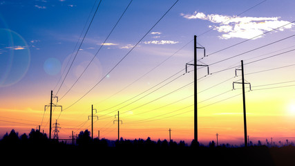 The last rays of the sun. Electricity pylons technology on sunset time background. Electric...