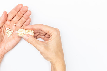 Hands holding a glass bottle and pills on a palm, patient taking pills and following doctor prescription, copy space