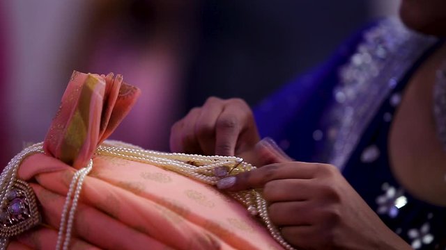 Traditional decoration being placed on a mans turban, sehra, at an Indian wedding. HD 24FPS.