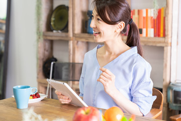 部屋でタブレットコンピューターを見る女性