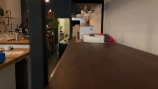 Dolly shot. Blurred picture interior. Coffee shop, bar, restaurant. Wood table. Movement on the table. Workers walking. Blur 4k stock footage 
