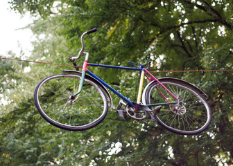 Fototapeta na wymiar Multi-colored bicycle hanging in the air among the trees in the park