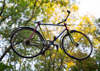 Fototapeta premium Multi-colored bicycle hanging in the air among the trees in the park