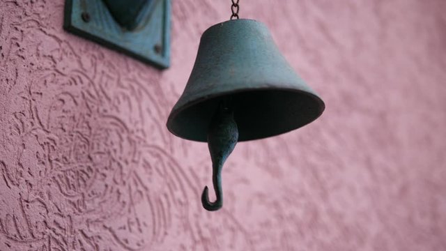 Person Rings Old rusty Antique Doorbell hanging on the wall. Pink wall. Isolated close-up.