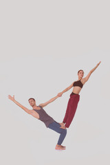 Fototapeta na wymiar Young athletic couple practicing acroyoga. Balancing in pair.