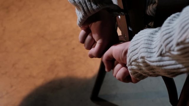 Hands of a man handcuffed to a chair trying to break free
